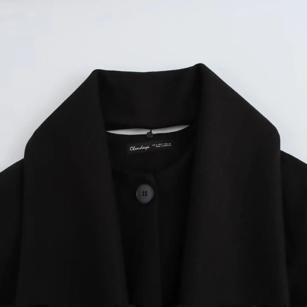 Women's long black overcoat with artificial fur collar, showing extended length and street fashion style.