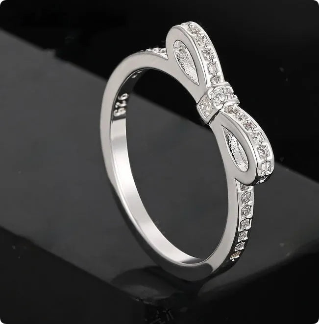Silver-colour bow ring with zircon crystal details on a white background.