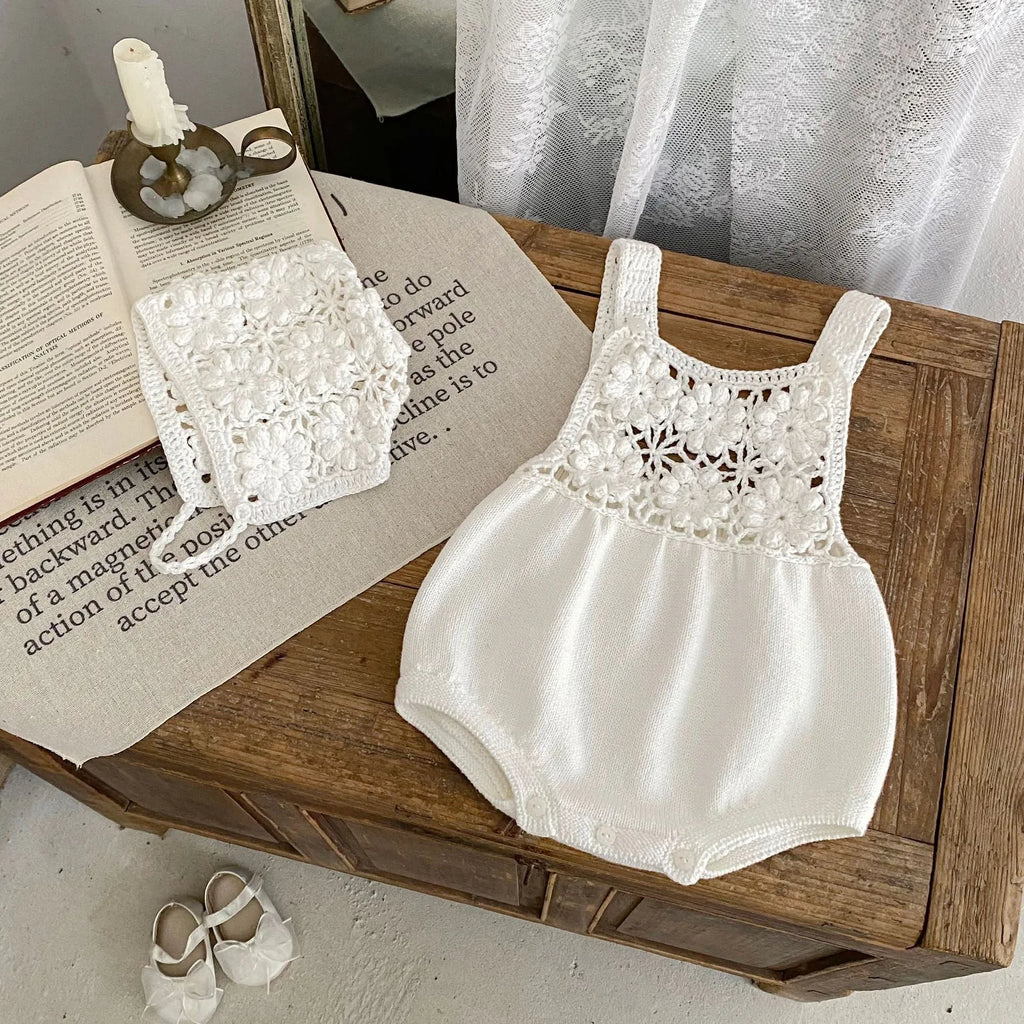 Beige baby romper with flower cutout strap and matching hat on a baby girl