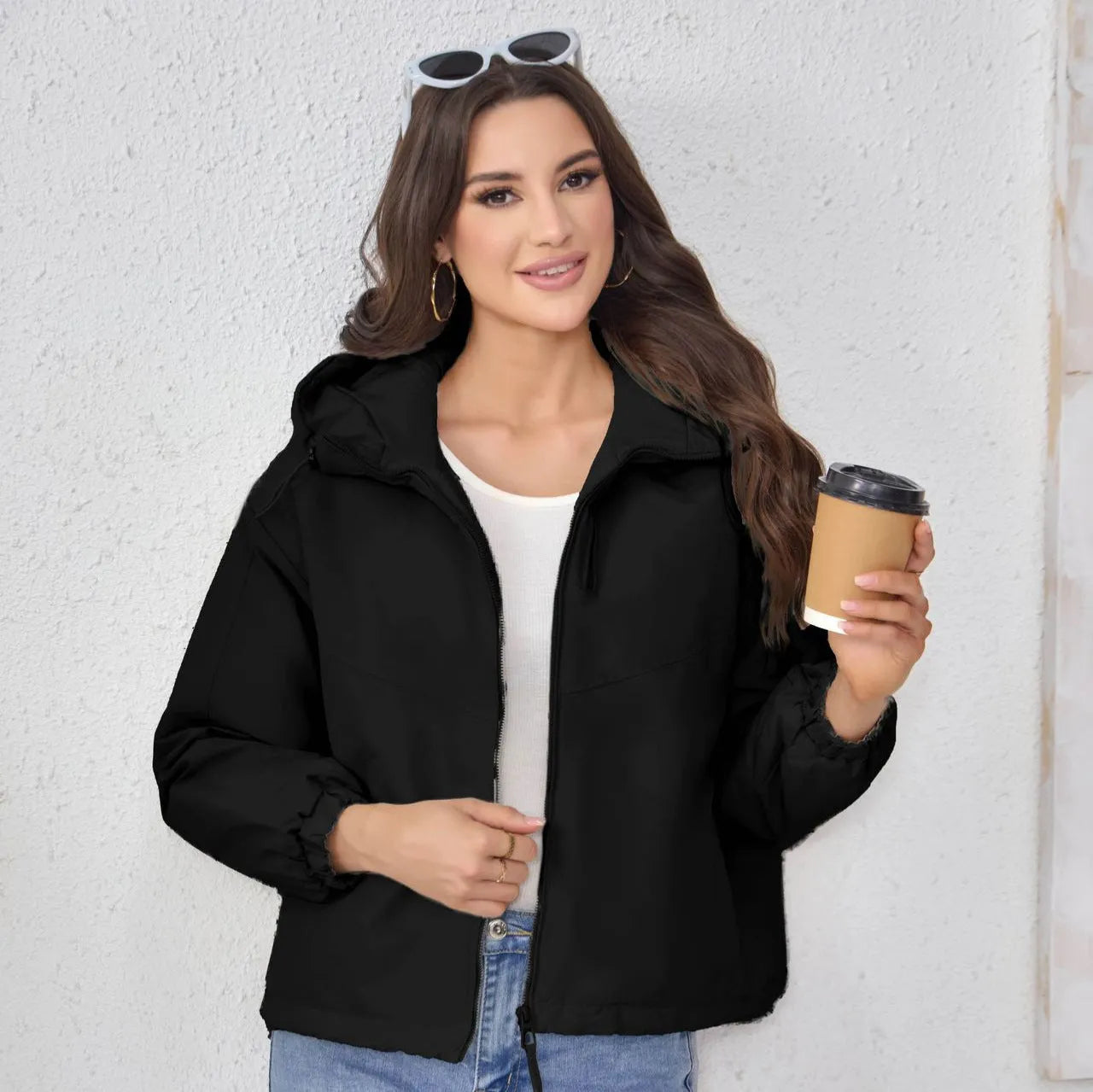 A woman wearing a loose-fitting grey hooded shell jacket with long sleeves, showing the front zip closure.