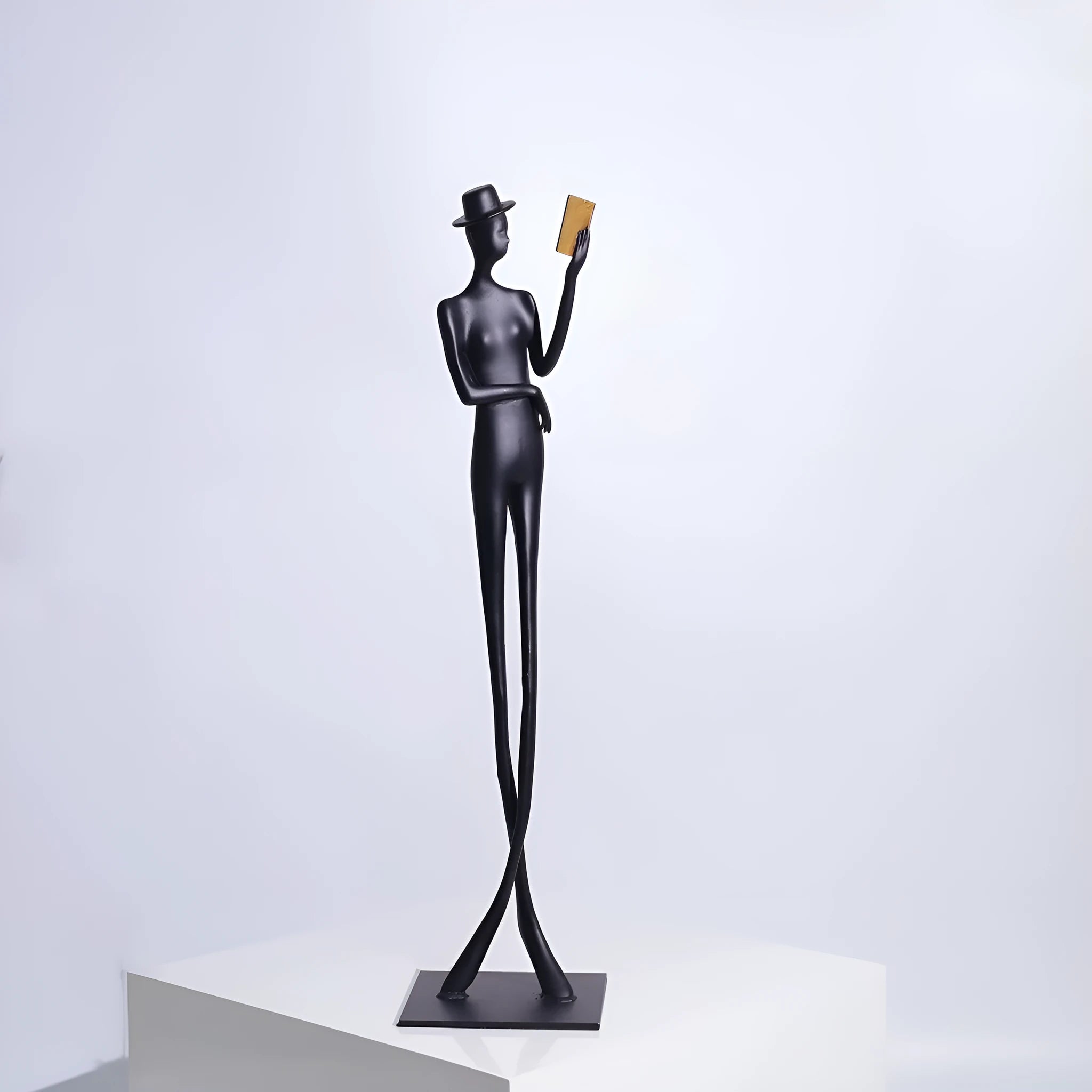 Black metal sculpture of a woman reading, modern aluminium desktop ornament.