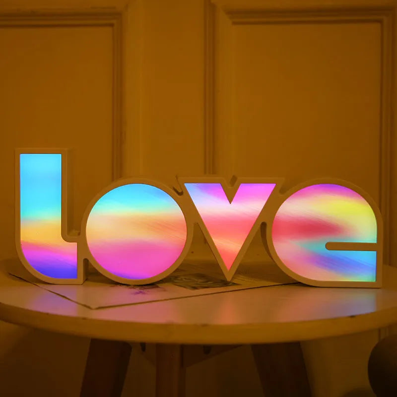 Rainbow-style plastic LED decorative light spelling LOVE, shown on a table.