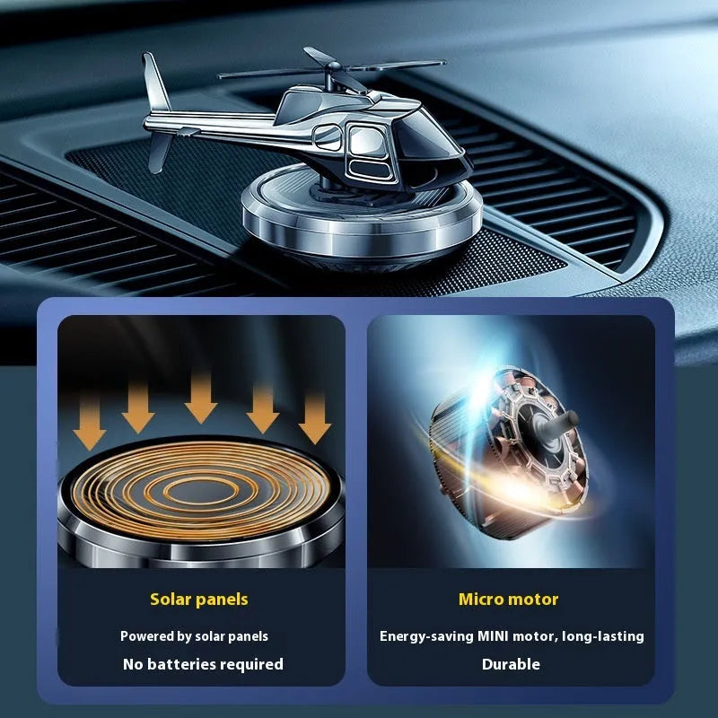 Silver metal solar-powered helicopter car ornament with rotating blades on a car dashboard.