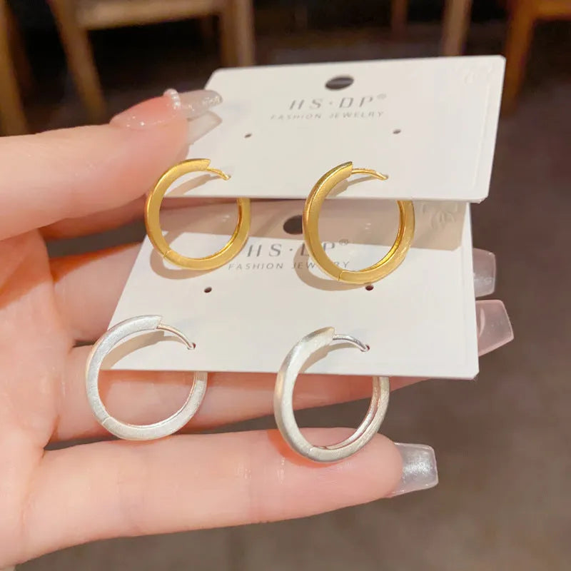 A pair of geometric circle ear clips for women in gold or silver finish.