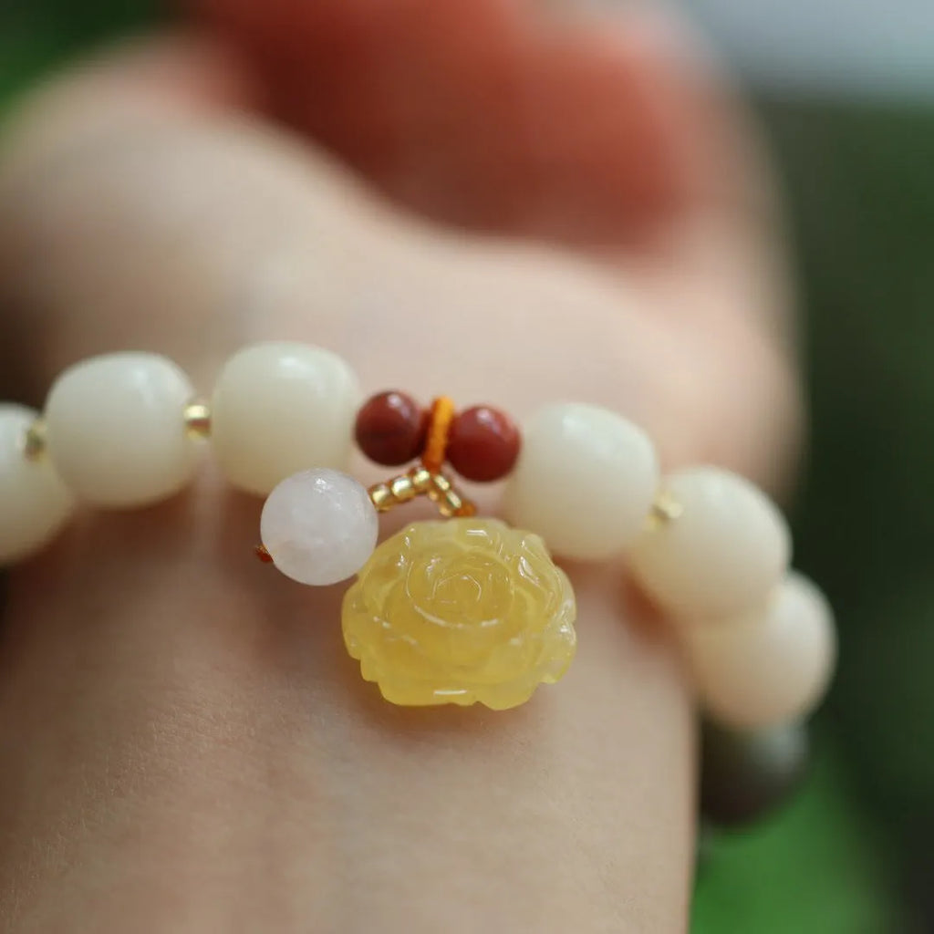 Close-up of a woven gradient white jade and Bodhi root bracelet with flower-shaped beads and a lotus accent.