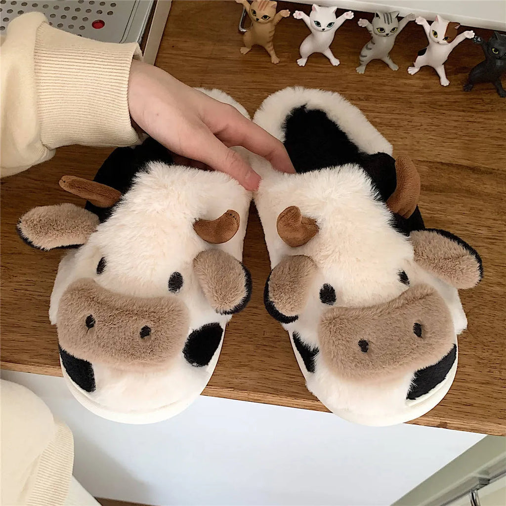 White cartoon cow slippers with plush faux fur and a textured non-slip sole.