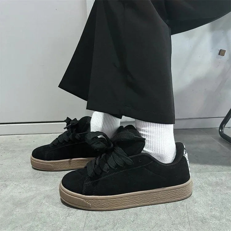 Black retro low-top sneakers with a platform sole and front lace-up closure on a white background.