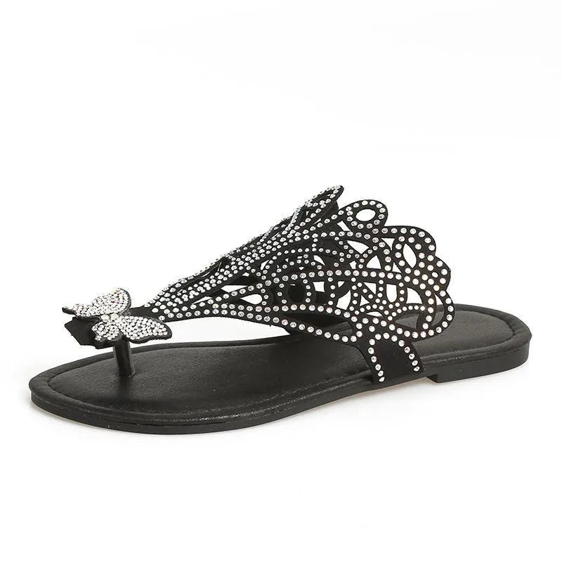 Women's black slip-on sandals with rhinestone details and flip-toe design on a white background