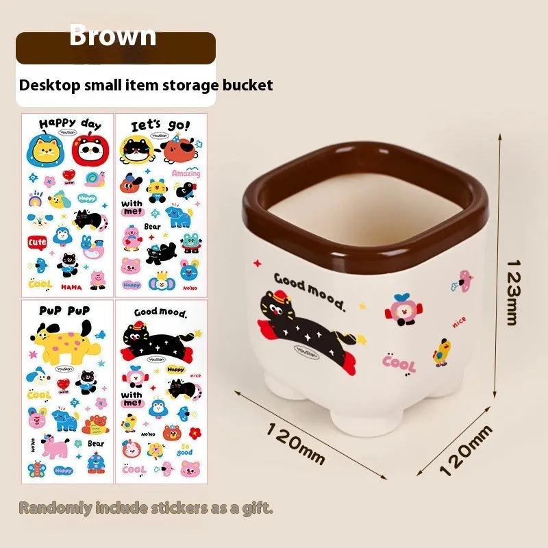 Cartoon-style plastic desktop organiser with various red and brown storage boxes and a pen holder.