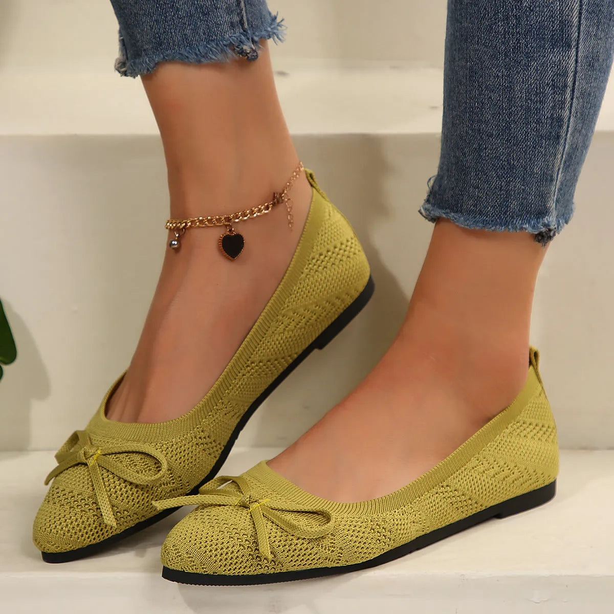 Women's knitted loafers with bow decoration in various colours showing flat rubber soles