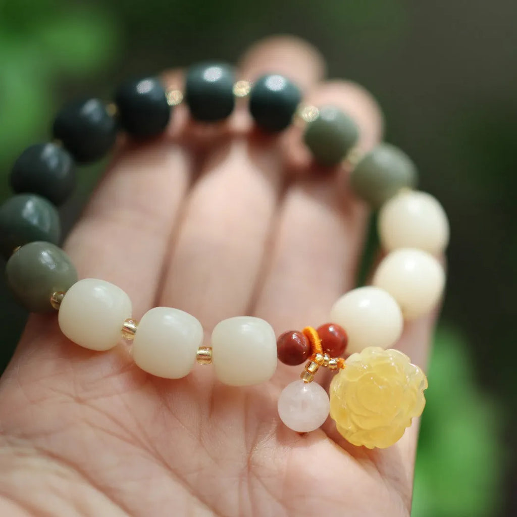 Close-up of a woven gradient white jade and Bodhi root bracelet with flower-shaped beads and a lotus accent.