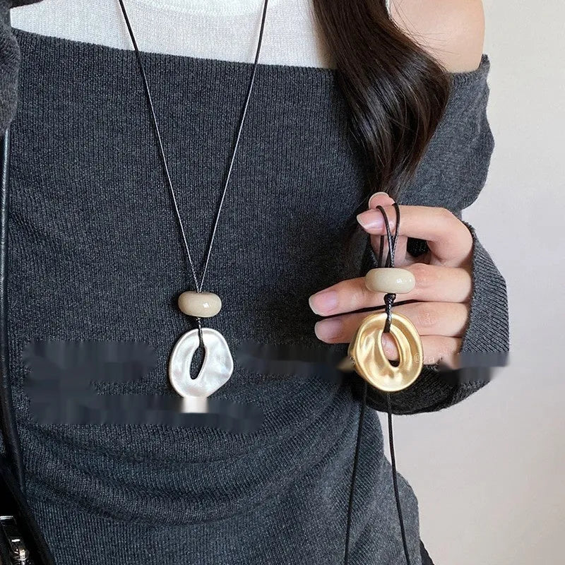 Gold long geometric bow pendant necklace with artificial crystal accents on a white background