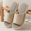 Women's open-toe linen slippers in light brown on a wooden floor, showing the breathable design and thickened sole.