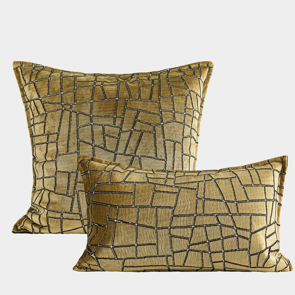 Gold geometric patterned decorative pillow on a grey sofa.