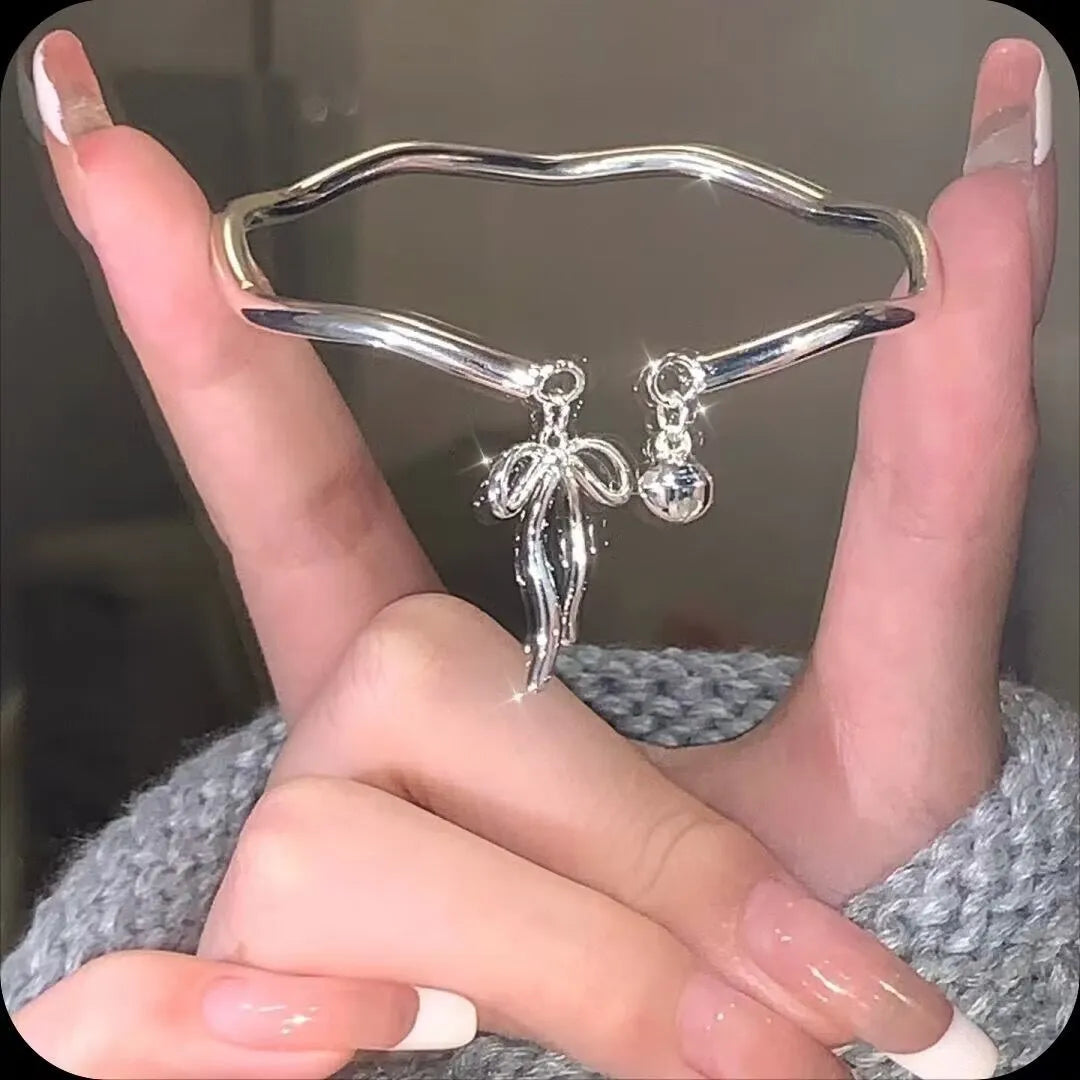 Silver adjustable bracelet with bow charm and bell opening mechanism