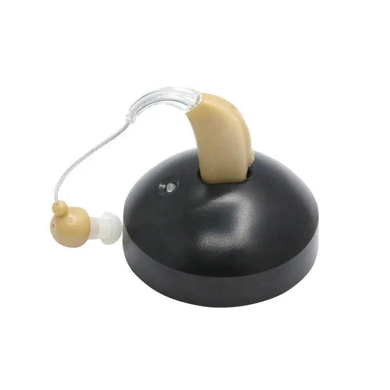 Black silicone rechargeable hearing aid amplifier for elderly users on a charging cable.