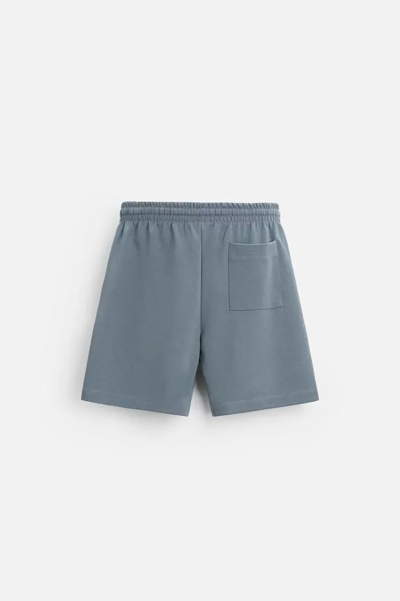 Man wearing a loose blue short sleeve top and matching blue shorts from a casual loungewear set.