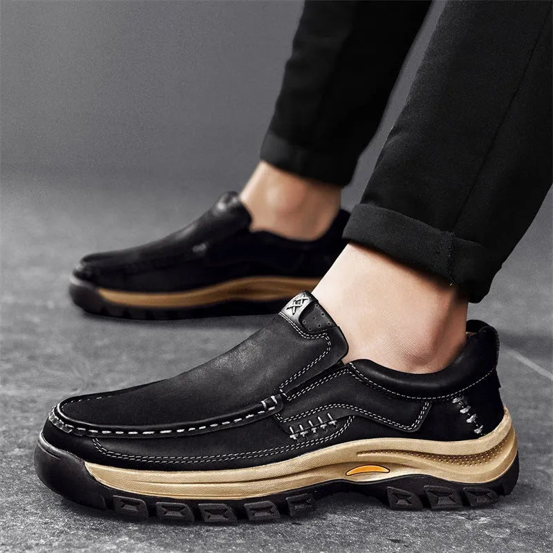 Men's black thick-soled mountaineering leather shoes with round toe and visible stitching on a natural background.
