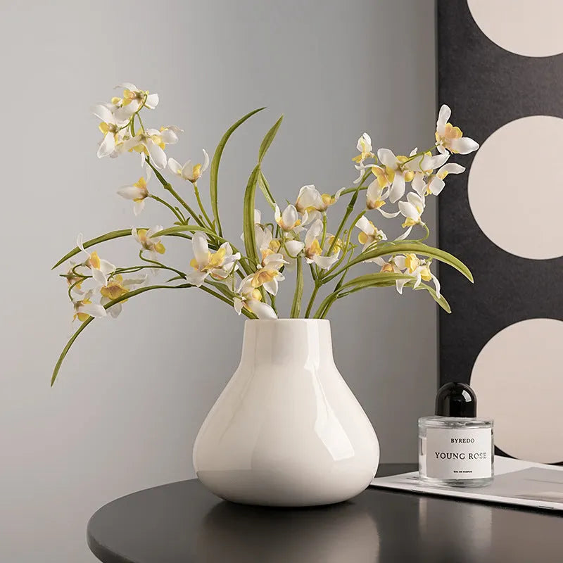 Black and white ceramic round belly french style decorative vase with two artificial flowers.