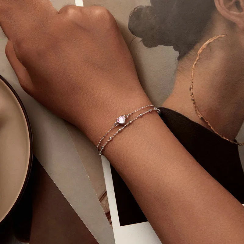 Women's sweet style sterling silver heart bracelet with adjustable chain on white background.