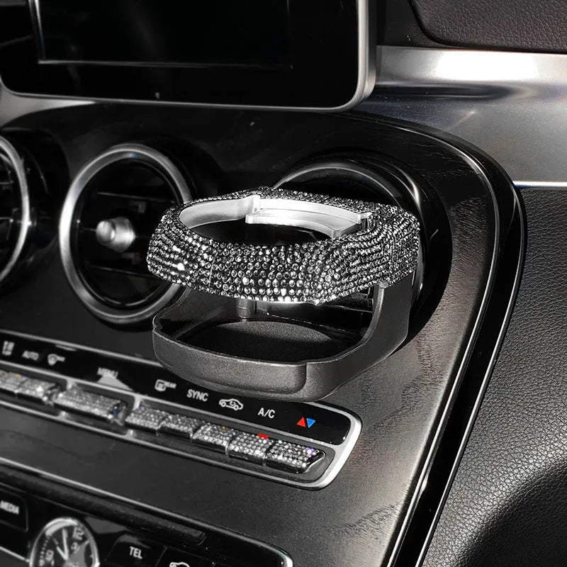 White diamond rhinestone car air vent cup holder bracket on a grey car dashboard.