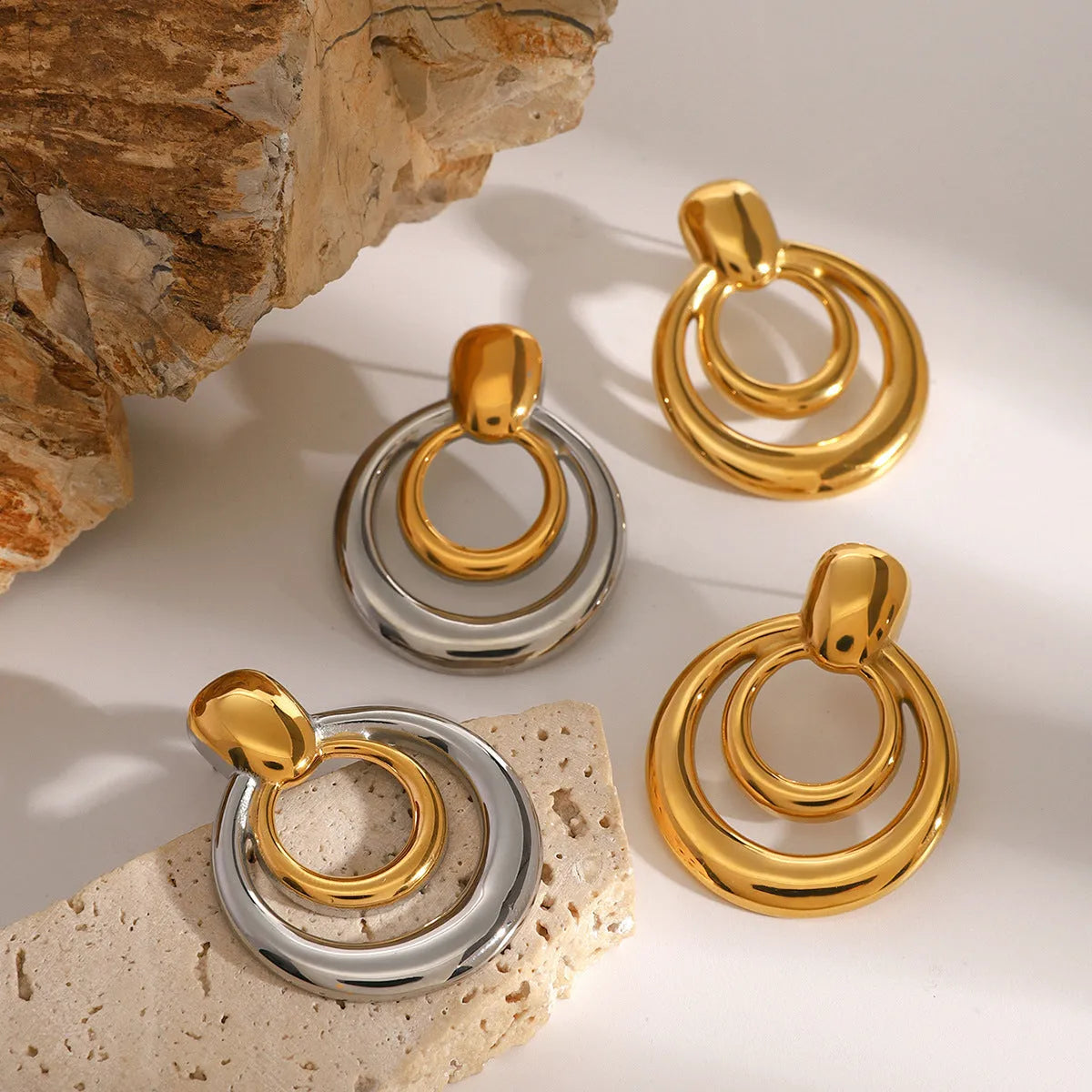 Gold-plated geometric stud earrings with hollow double-layer round design on titanium steel backing.