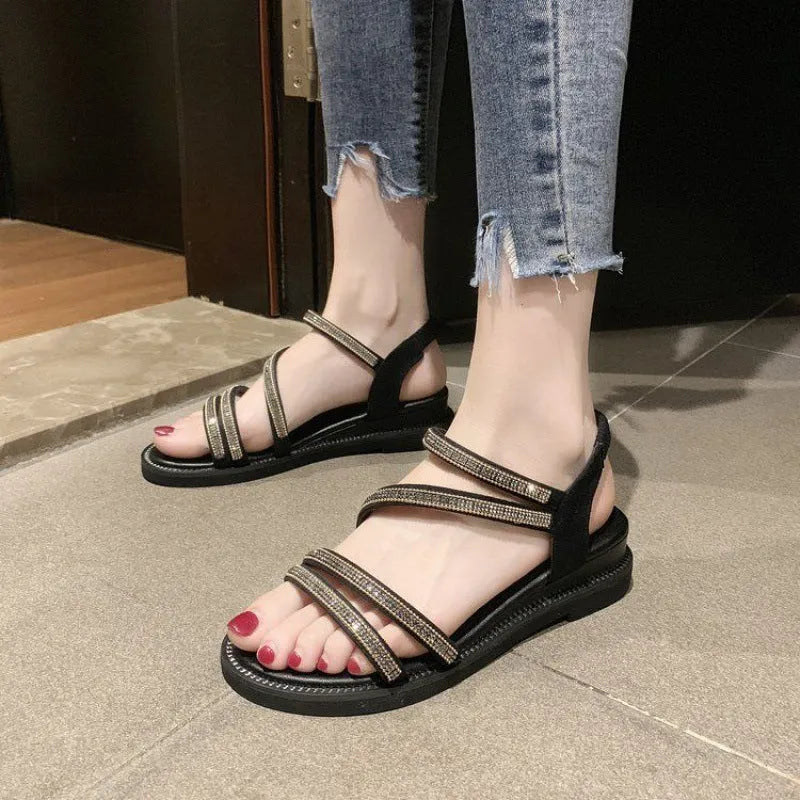 Women's flat casual sandals in gold with rhinestone details and an elastic band.