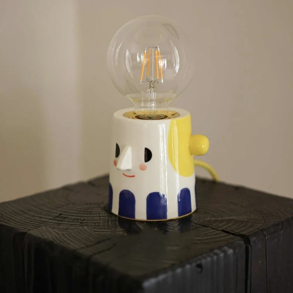 Handmade ceramic lamp with ball headlight design on wooden surface