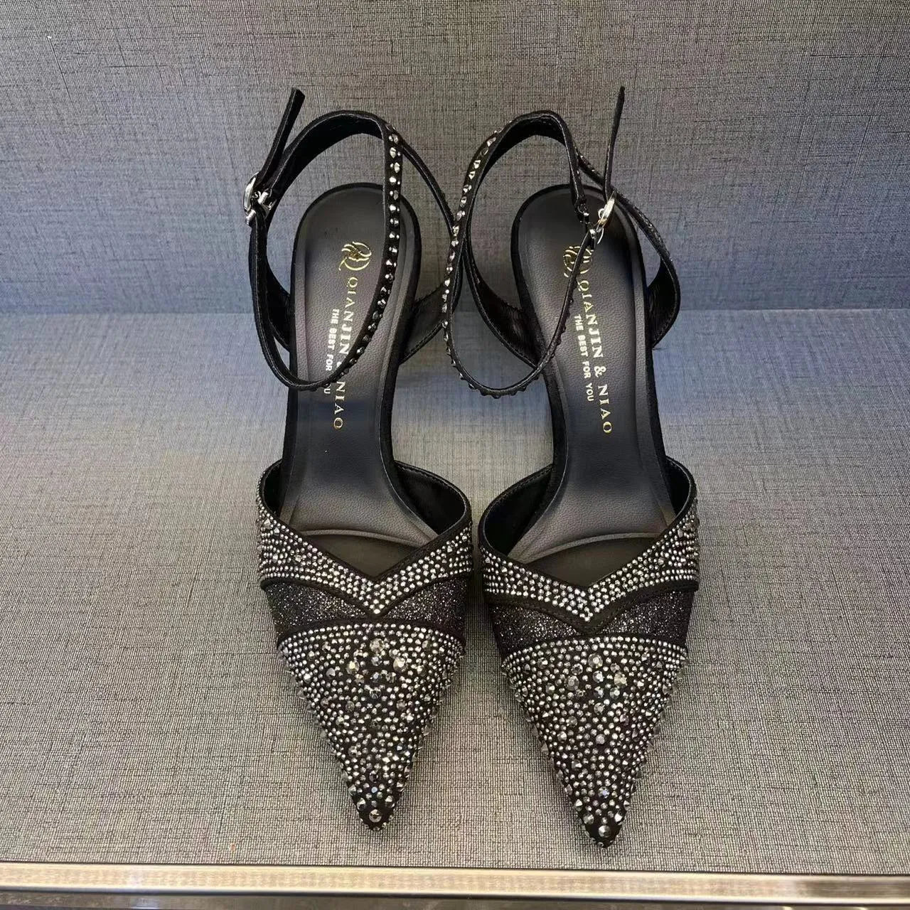 Women's black hollow high heel with stiletto heel, pointed toe, and red sole on a light background.