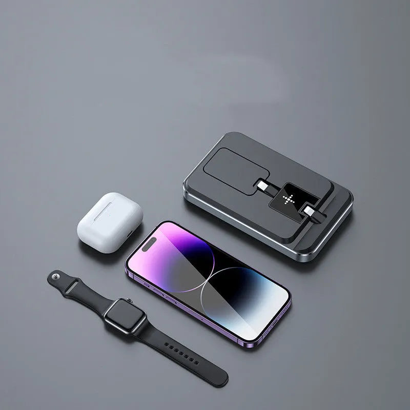 Flat folding three in one wireless charger in black with phone, watch, and headphones placed on charging zones