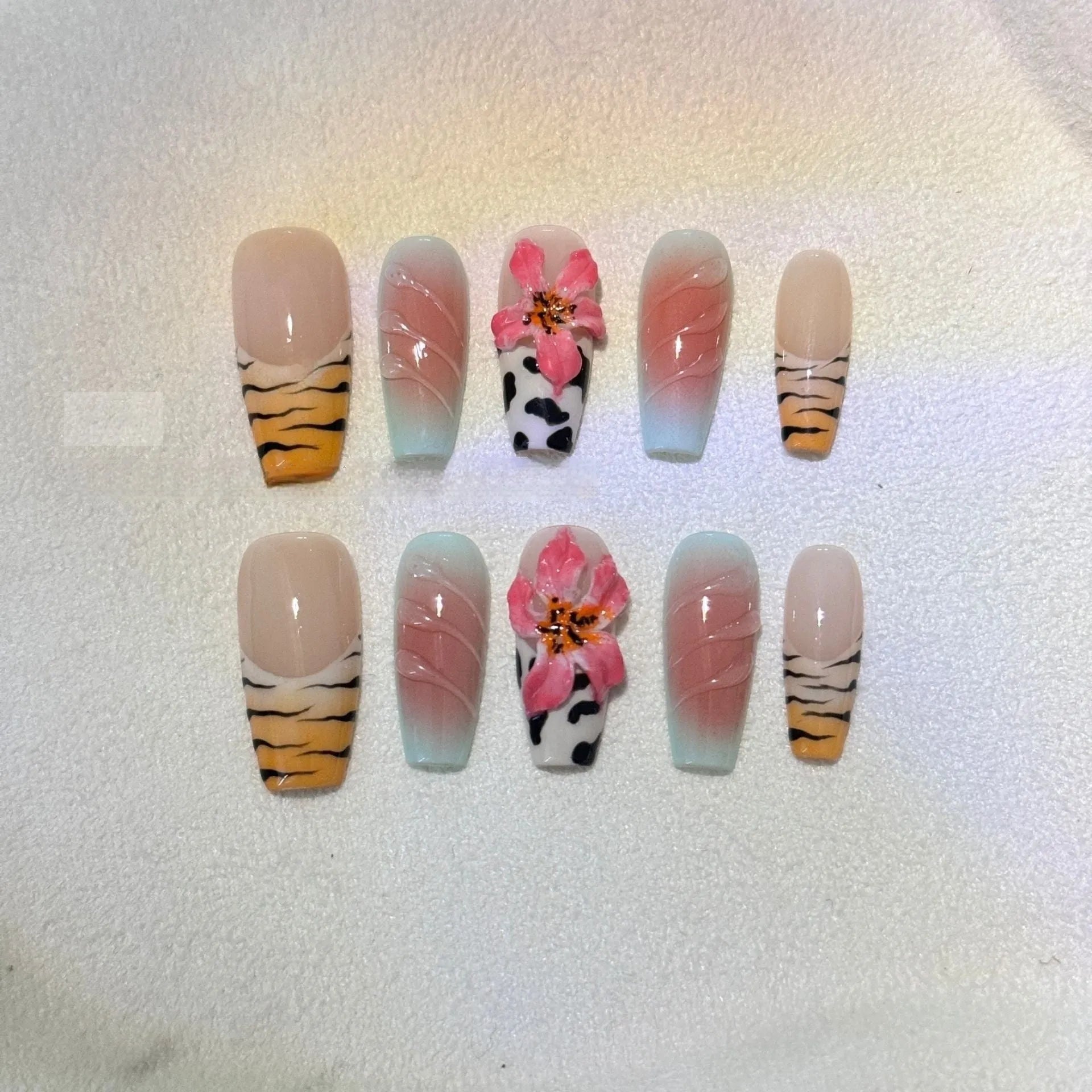 Hand-carved artificial nails with raised zebra pattern and floral designs, shown in long style.