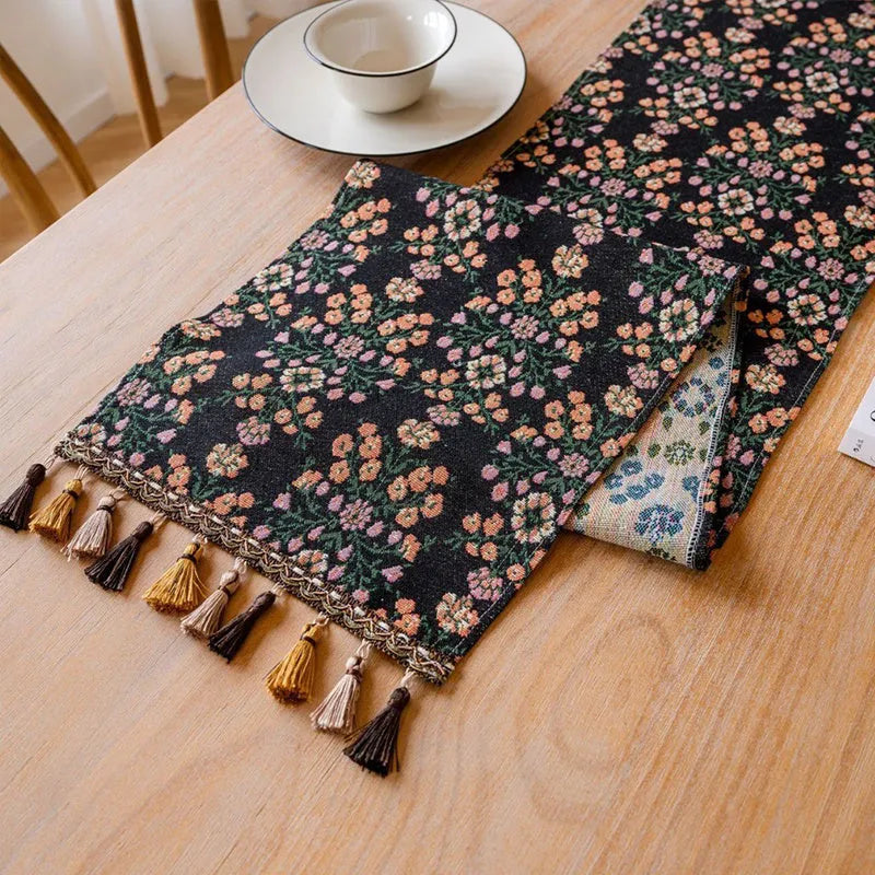 Rhyme Nordic jacquard table runner with tassel trim in a striped pattern, laid flat on a wooden table.