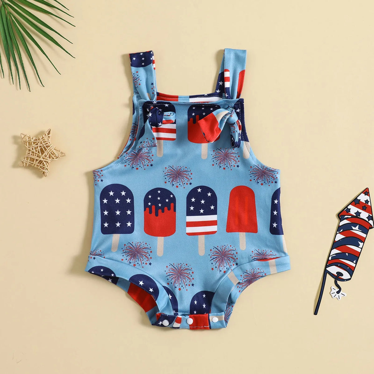 Baby girl wearing a sleeveless knotted front suspender pants jumpsuit in a printed design.