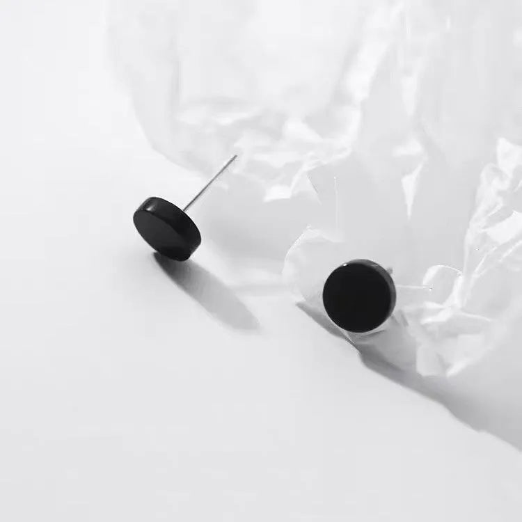 A pair of flat, round sterling silver S999 bone stud earrings on a plain background, showing silver and black colour options.