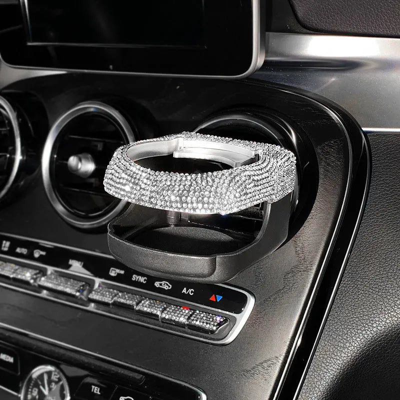 White diamond rhinestone car air vent cup holder bracket on a grey car dashboard.