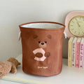 Foldable cotton laundry basket featuring an illustrated design, shown in a bedroom setting.