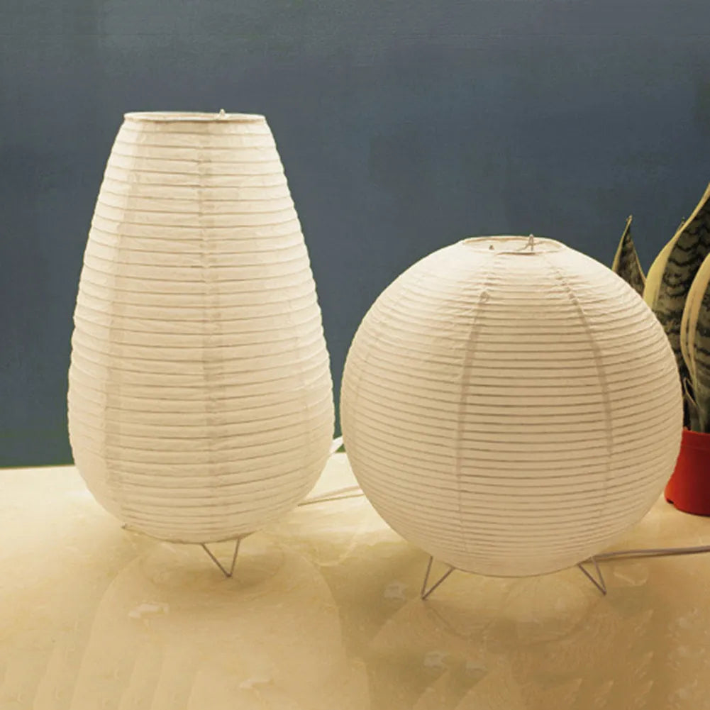 White rice paper plug-in table lamp in circular shape on a wooden bedside table.