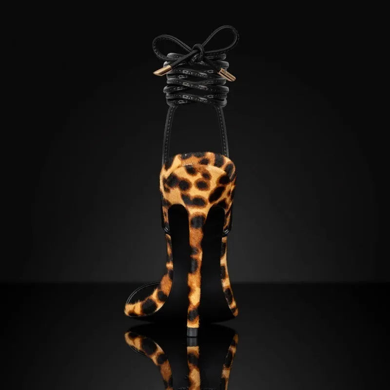 Leopard print women's Roman sandals with pointed toe, lace-up ankle strap, and buckle closure.