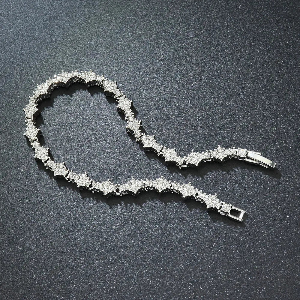 Flower-shaped cross tennis chain bracelet in gold alloy on white background showing diamond and geometric detailing