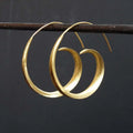Gold alloy geometric round spiral leaf ear studs with electroplated finish on white background