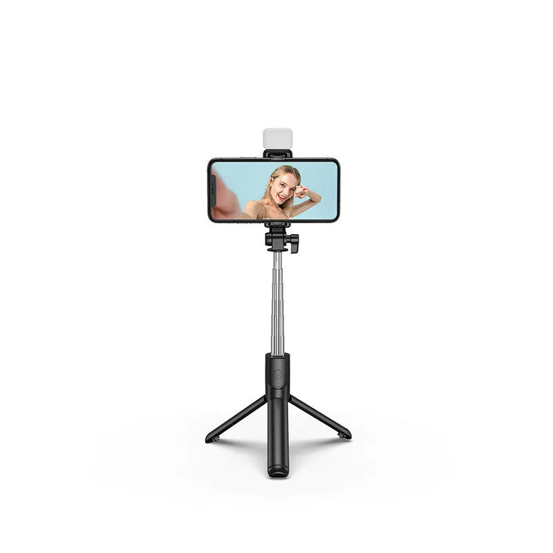 Black Bluetooth selfie stick with extended tripod legs holding an iPhone, showing its 360-degree rotating phone holder.