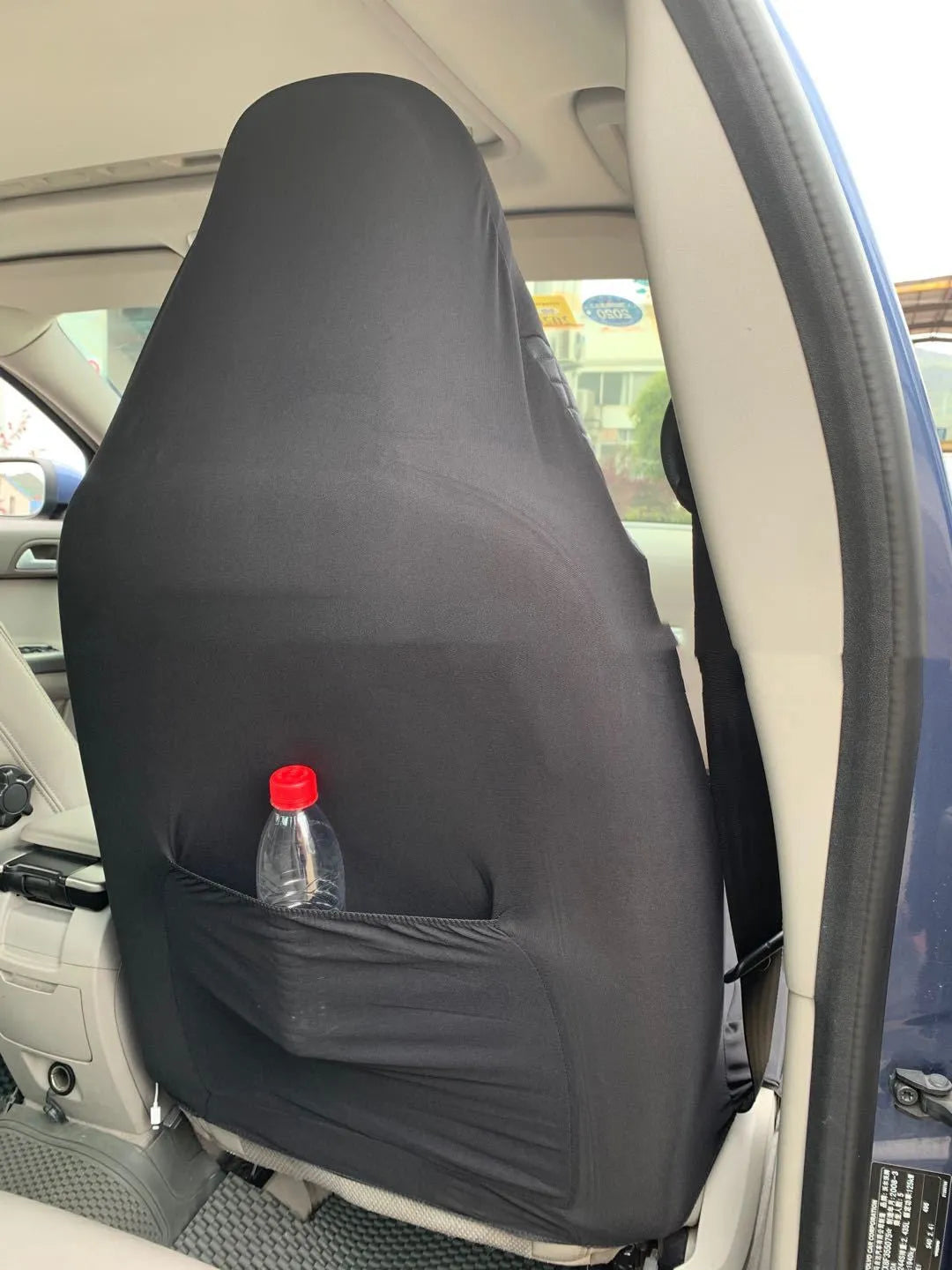 Black quilted automotive seat cover made of PU and polyester with plastic hooks.
