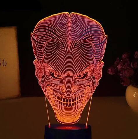 3D acrylic LED lamp displaying coloured light on a desk, with a remote control and USB cable