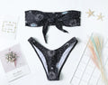 Black one-piece swimsuit with bikini print pattern and split tube top design.