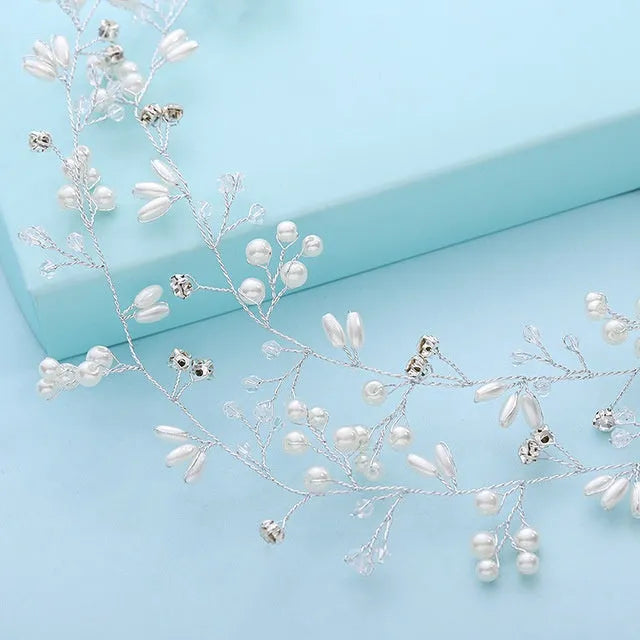 Close-up of a silver bride's hair band with pearls and crystals on a wired base.