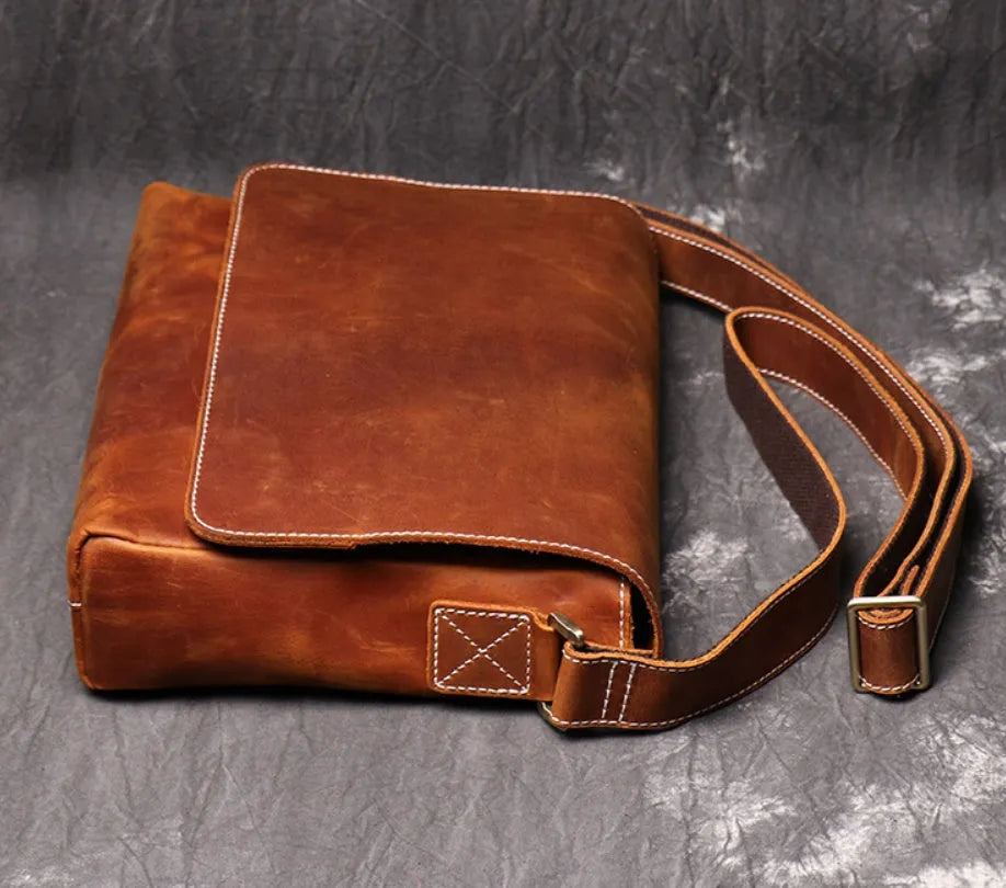 Brown vintage leather men's messenger bag with a shoulder strap showing internal organiser pockets.