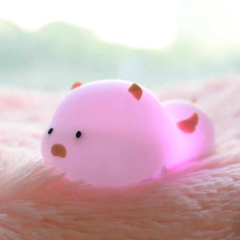 Pink silicone pig-shaped night light with touch control on bedside table
