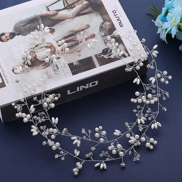 Close-up of a silver bride's hair band with pearls and crystals on a wired base.