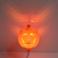 A plastic pumpkin lamp with a USB port, glowing in either yellow or purple light.