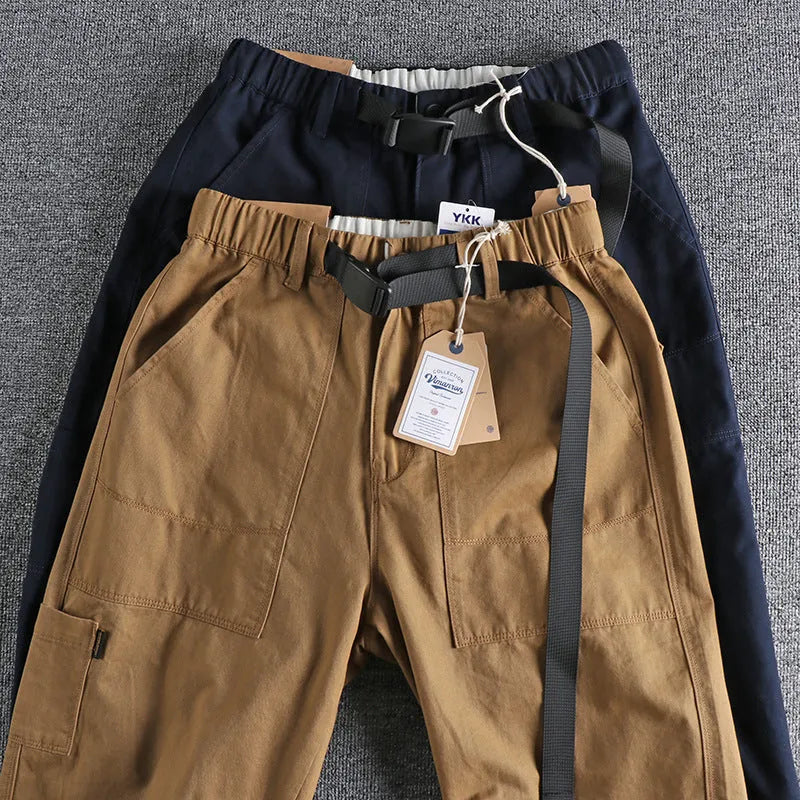 Men's khaki cotton work trousers with a buckle belt and three-dimensional cut on a hanger.